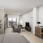 A cozy bedroom featuring a bed with decorative bedding and pillows, a nightstand beside it, and a desk against the wall. There are cabinetry and a chest of drawers in the room, along with a television mounted on the wall.