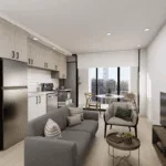 A cozy living room featuring a comfortable couch facing a television, with cabinetry and decorative elements adorning the walls. The floor is well-maintained, and the overall ambiance reflects modern interior design.